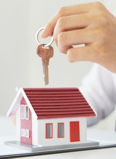 Person holding a key on top of a toy house